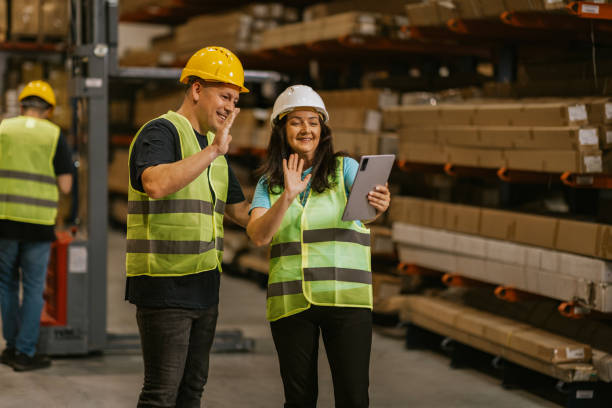 istock Two warehouse workers in safety vests video chatting on a tablet 2161189350