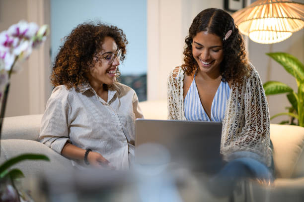 istock Sisters relaxing on the sofa with laptop 2161189849