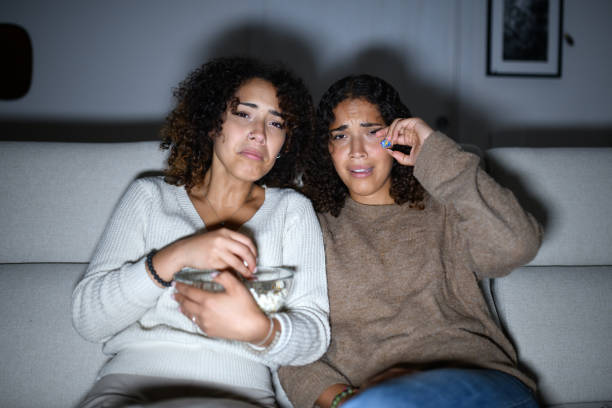 istock Sisters watching TV on sofa: Sad romantic movie 2161190682