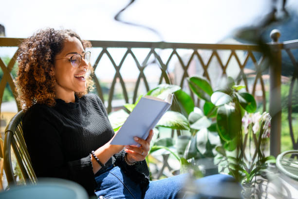 istock Woman reading book on the balcony 2161192324