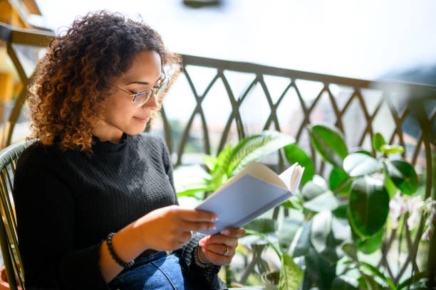 istock Woman reading book on the balcony 2161192363