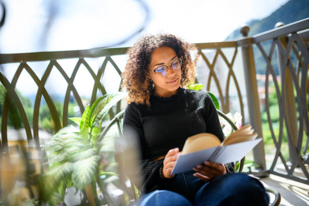 istock Woman reading book on the balcony 2161192402