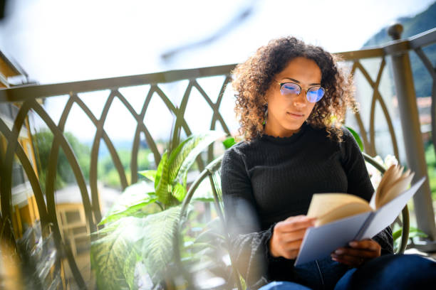 istock Woman reading book on the balcony 2161192432