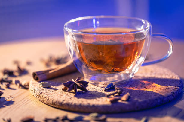 Fragrant black tea with spices on the table, close-up on a blurred background.
