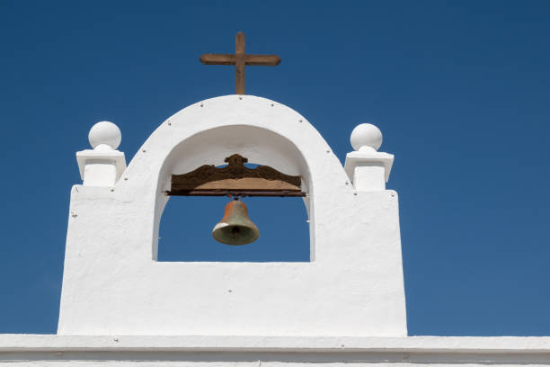 Traditional white color of the facade of the building. Small church with a belfry and a cross. Masdache, Lanzarote, Canary Islands, Spain.