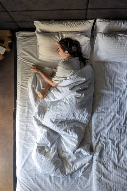 istock A young woman lying under a blanket, sleeping on a soft pillow, top view. 2161194516