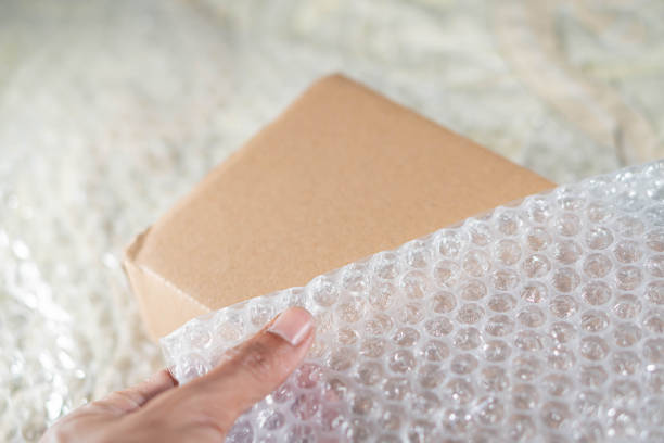 istock Hand holding bubble pack with cardboard box in background 2161202894