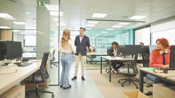 istock Office manager discussing with employee in a busy modern office. 2161204225
