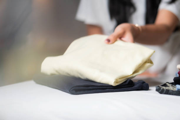 istock Person folding clothes with a yellow shirt on top 2161205077