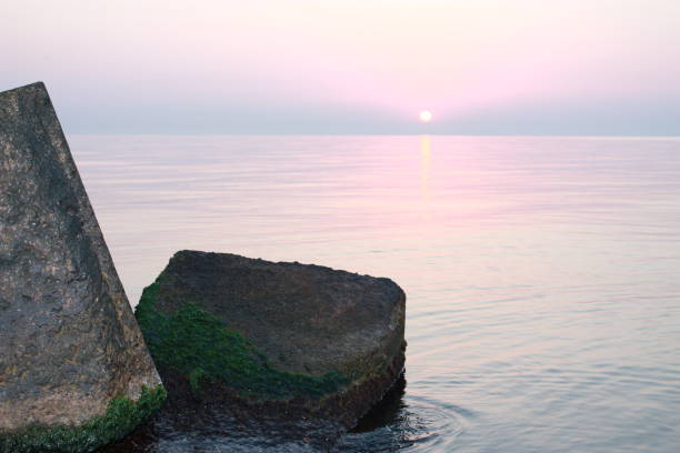 Serene pink sky at sunset over a tranquil sea, casting a soft, calming glow on the water's surface