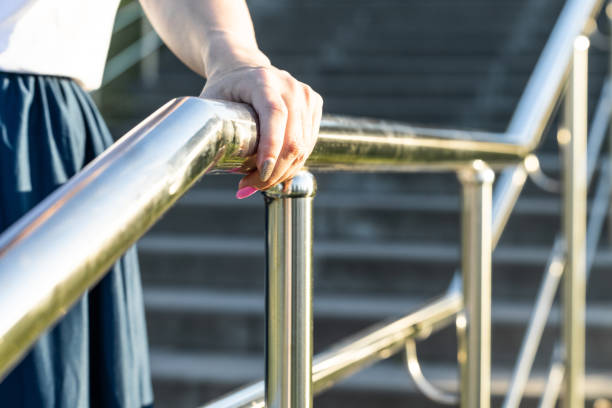 istock woman's hand holding onto the metal staircase railing. 2161211315