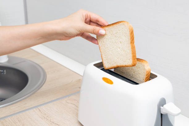 istock woman's hand putting bread into the toaster, close-up 2161211333