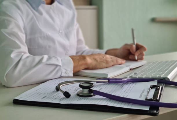 istock Doctor Writing Notes in Examination Room 2161213812