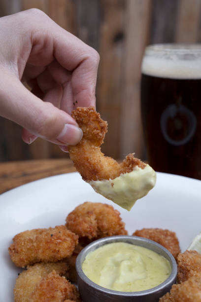 istock A man holding a fried shrimp dipped in aioli 2161215783
