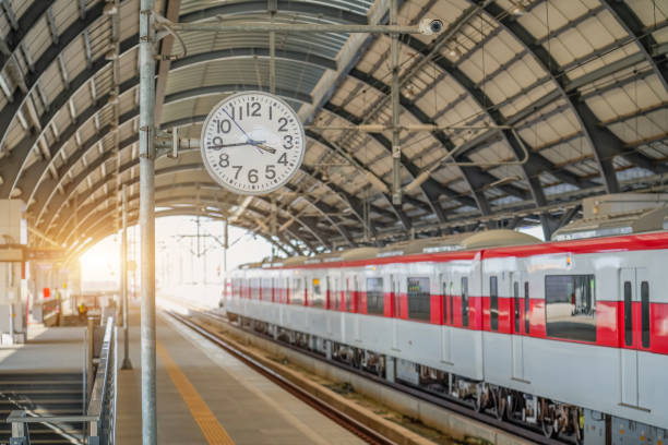 istock Clock on a pole on the passenger platform at a train station awaiting the arrival of a commuter electric train. 2161230493
