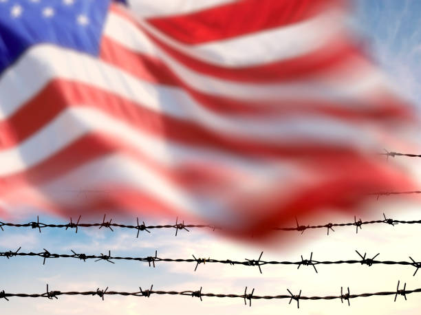 istock Waving American flag over barbed wire fence 2161230865