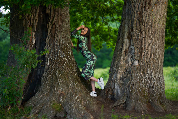 Gorgeous Hispanic young woman beauty model in green dress in a forest with centennial oak trees