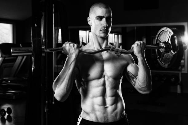 istock Man In The Gym Exercising Biceps With Barbell 2161241965