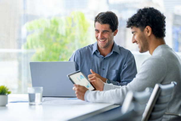 istock Two businessmen working on a digital tablet and laptop computer in the office. 2161243135