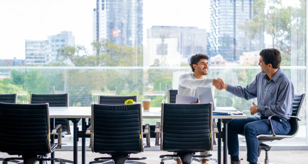 istock Handshake between Two businessmen working on a digital tablet and laptop computer in the office a board room or meeting room. 2161243456