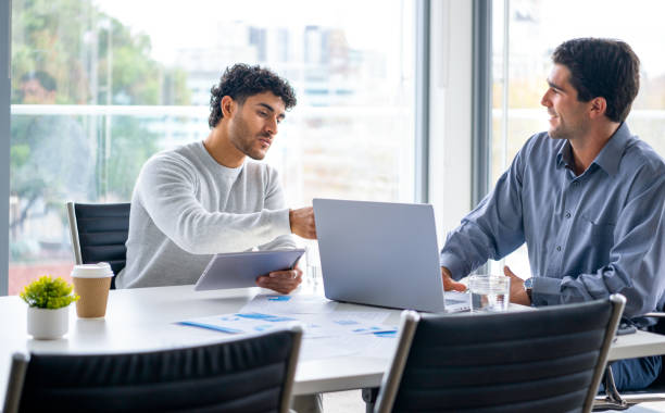 istock Two businessmen working on a digital tablet and laptop computer in the office a board room or meeting room. 2161243561