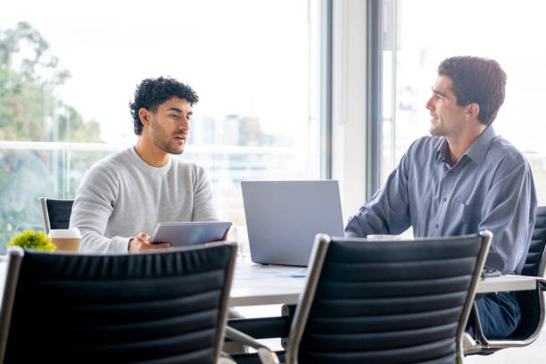 istock Two businessmen working on a digital tablet and laptop computer in the office a board room or meeting room. 2161243607