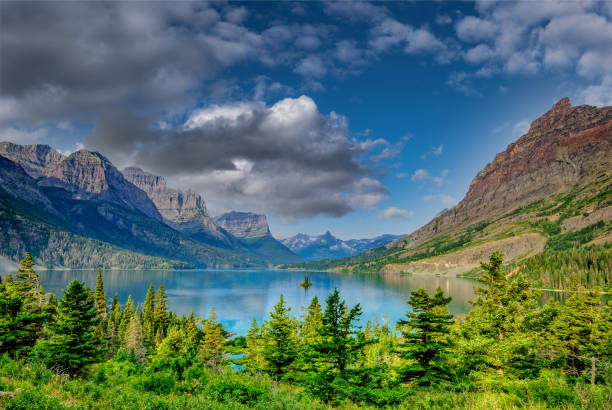 Saint Mary Lake, on the east side of the Continental Divide, is the second largest lake in Glacier National Park.  This lake marks a meeting point between the Rocky Mountains and the Great Plains, providing some great mountain vistas from its shores.  Abruptly rising from the west end of the lake are Little Chief, Gunsight and Fusillade Mountains.  In the middle of the lake is tiny Wild Goose Island providing an iconic view that was featured in the opening credits of the movie “The Shining”.  This scene of Saint Mary Lake and Wild Goose Island was photographed from the Wild Goose Island Overlook on the Going to the Sun Road near Babb, Montana, USA.