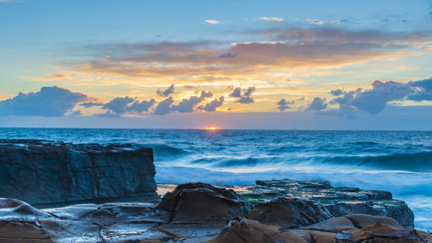 Sunrise, sea, waves, clouds and tessellated rock platform