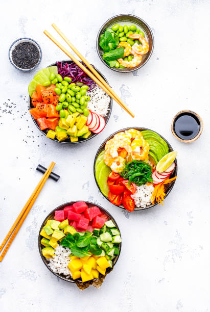Poke bowls with vegetables and seafood set for balanced diet, white table background, top view
