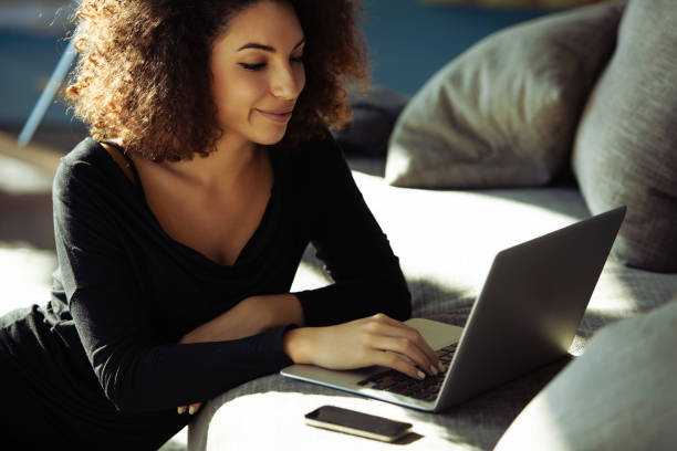 istock Young woman lying on sofa using laptop at home 2161267571