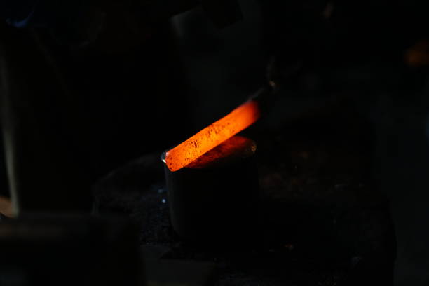 Red hot steel glowing in the dark, The blacksmith uses iron tongs to manage the shape of the Red hot metal