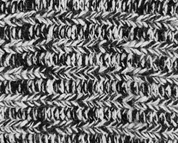 A detailed close-up of a white knitted textile showcasing textured patterns illuminated by soft natural light. Ideal for concepts of craftsmanship, warmth, and texture in design and fashion.