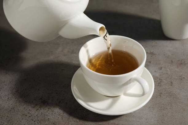 istock Pouring aromatic tea in cup at gray table, closeup 2161280238