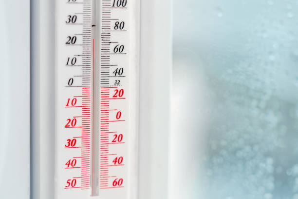 A close-up shot of a white plastic thermometer attached to a white window frame.