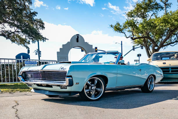 A hispanic man in his vintage lowrider convertible car, cruising on the streets in a neighborhood.