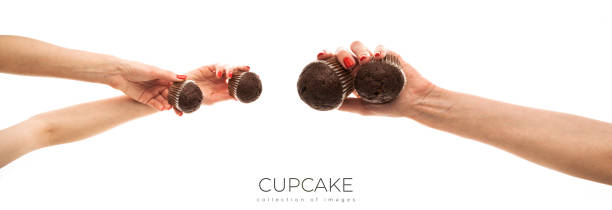 Female hand holds a brown chocolate cupcake isolated on white background
