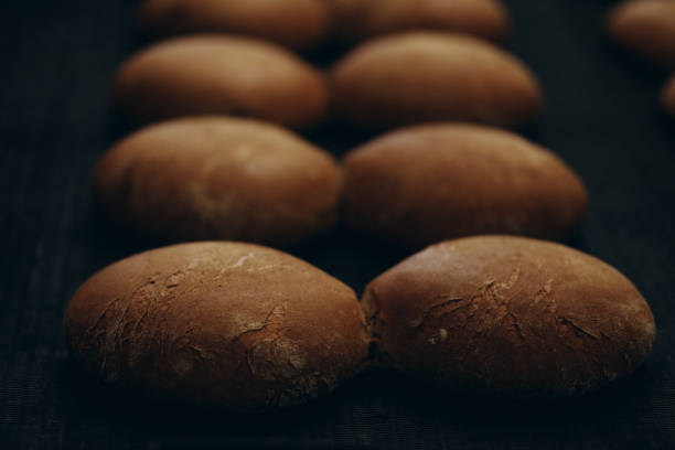 Fresh baked bread and wheat ears on a wooden background