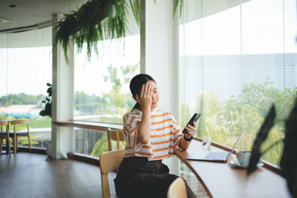 istock Asian woman sitting at coffee shop looking at smartphone screen and having problem. 2161295885