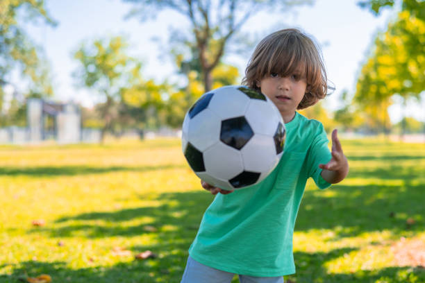 A Kid play football on outdoor field at the end of the day