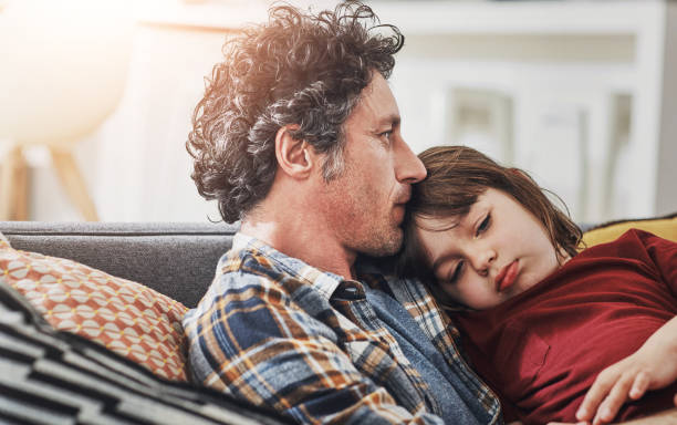 Dad, boy and sofa with support or comfort with talking, communication with love for development. Parent, male child and together in family home for relationship or bonding, trust and safety in lounge