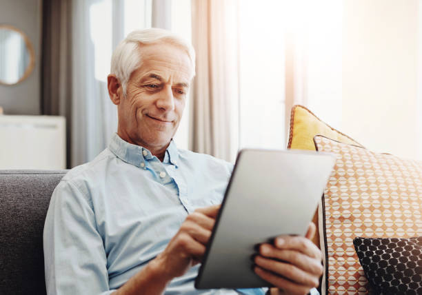 istock Senior man, technology and relax on sofa in home for typing email, communication and reading online news. Elderly person, tablet and retirement in lounge for bills payment, webinar and writing ebook 2161300585