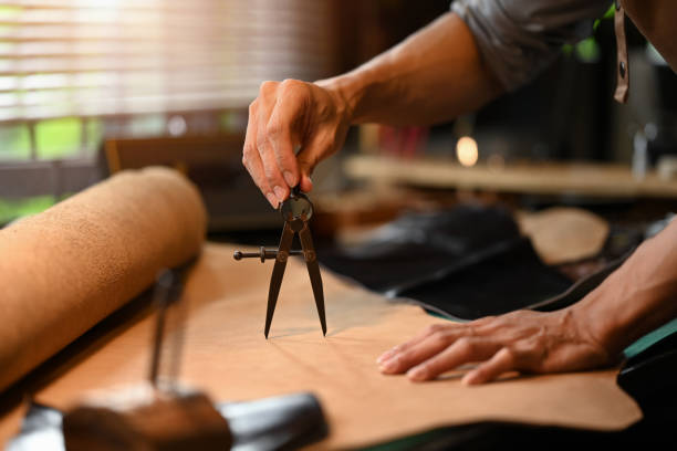 Close up shot of professional male artisan measuring leather piece on a workbench stock photo