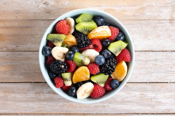 istock Fruit salad in a blue bowl on wooden table 2161303233