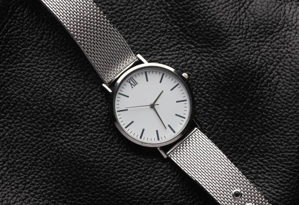 istock Women's analog silver wristwatch on a black leather surface 2161304413