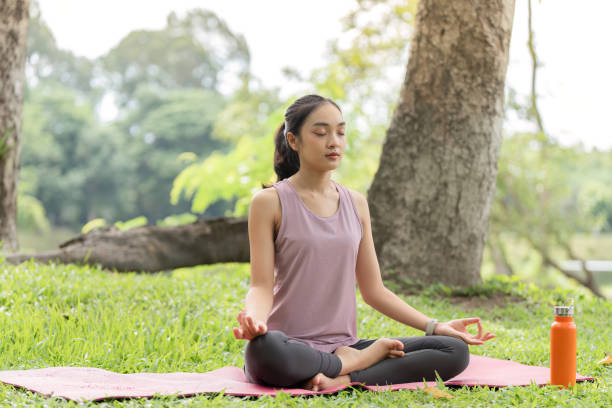 istock Woman Practicing Yoga and Relaxing in a Serene Park Setting with Lush Greenery and Trees 2161306852