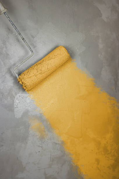 istock Worker painting wall surface with paint roller. Renovating apartment. Brush roller paints the wall with white yellow color for protection from corrosion. Empty copy space textured background. Close up 2161306865
