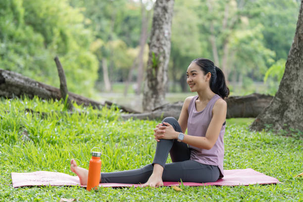 istock Woman Practicing Yoga and Relaxing on a Mat in a Serene Park Setting with Greenery and Trees in the Background 2161306898