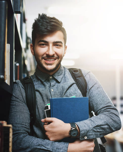istock University, library and portrait of man with books for knowledge, education or development. Scholarship, student and shelf with study material at campus for literature information, learning or growth 2161306909