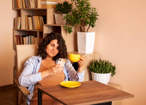istock Beautiful young woman uses smartphone and drinks coffee. 2161309425