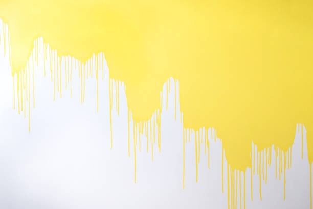 istock A half painted concrete white wall. Streams and drops of yellow paint on a white background. 2161310546